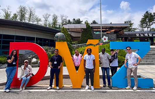 Whitman group posing outside by the DMZ logo