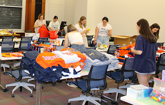 Students in a classroom packing Syracuse University products