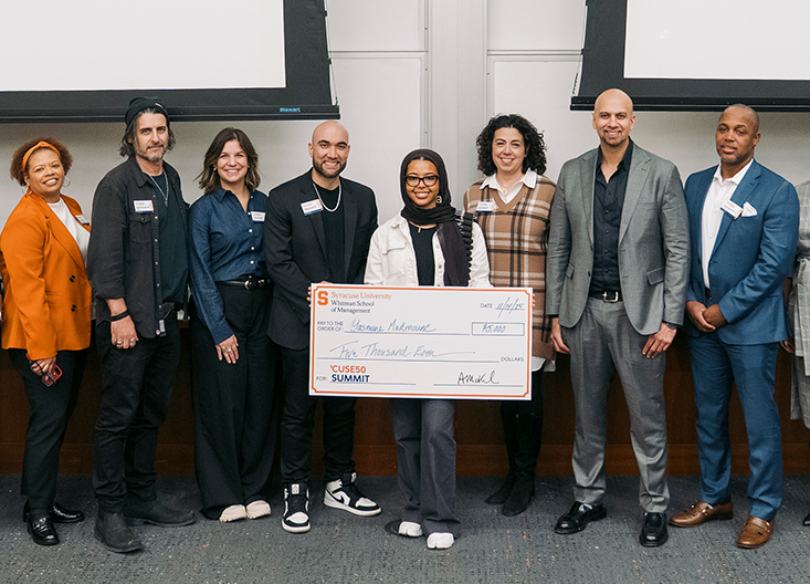 Pitch competition winner posing with oversized checks and judges