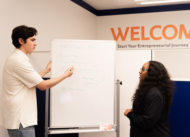 Student showing staff member something on whiteboard