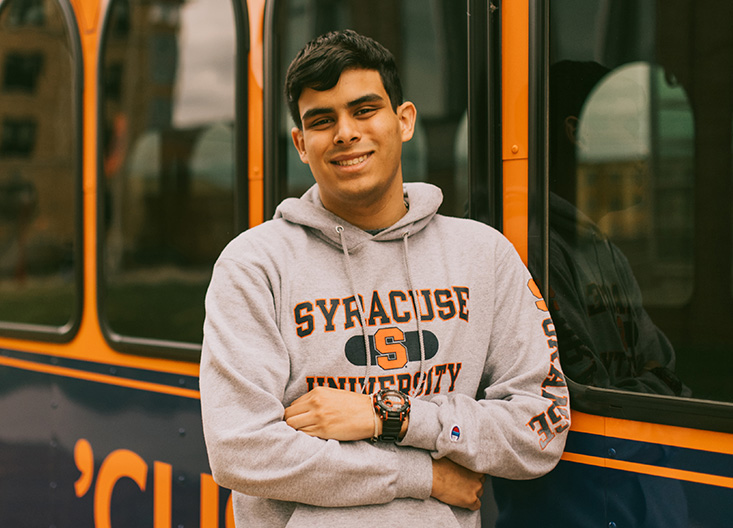 Student posing in front of university trolley