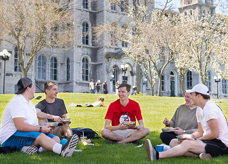 Five Syracuse students sitting outside in spring on the grass