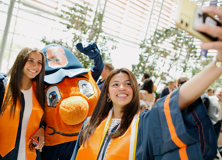 Students taking pictures with Otto the orange mascot