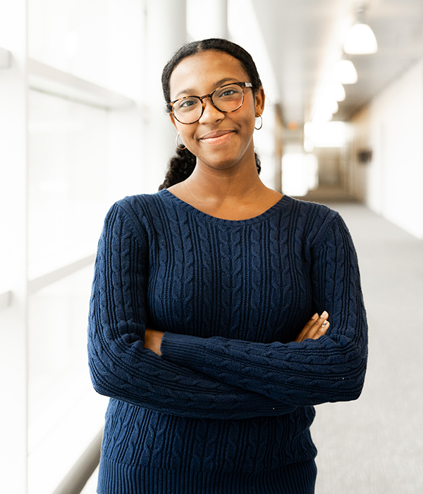 Student posing with arms crossed in hallway