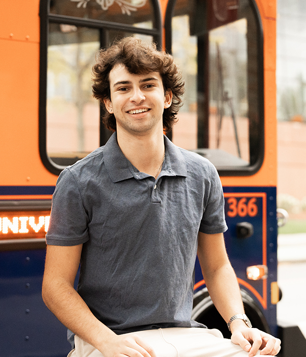 Student posing in front of Syracuse University trolley