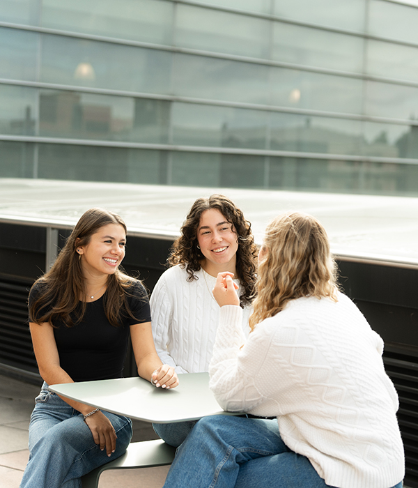 Clipped_UG_9_2024_600x700 Three students sitting by table on Whitman's terrasse