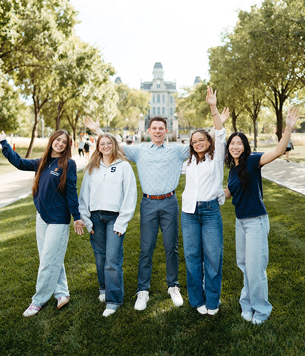Students cheering with Hall of Languages in the background