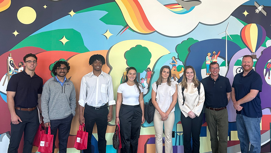 Mike Durkin posing with Whitman students in front of colorful mural