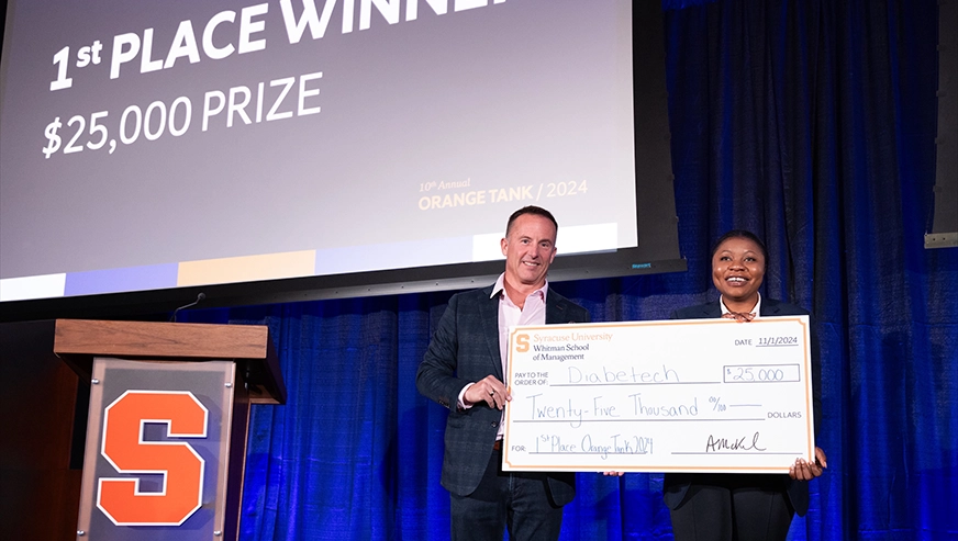 Tosin Alabi receiving an oversized check when winning the 2024 Orange Tank Business Pitch Competition