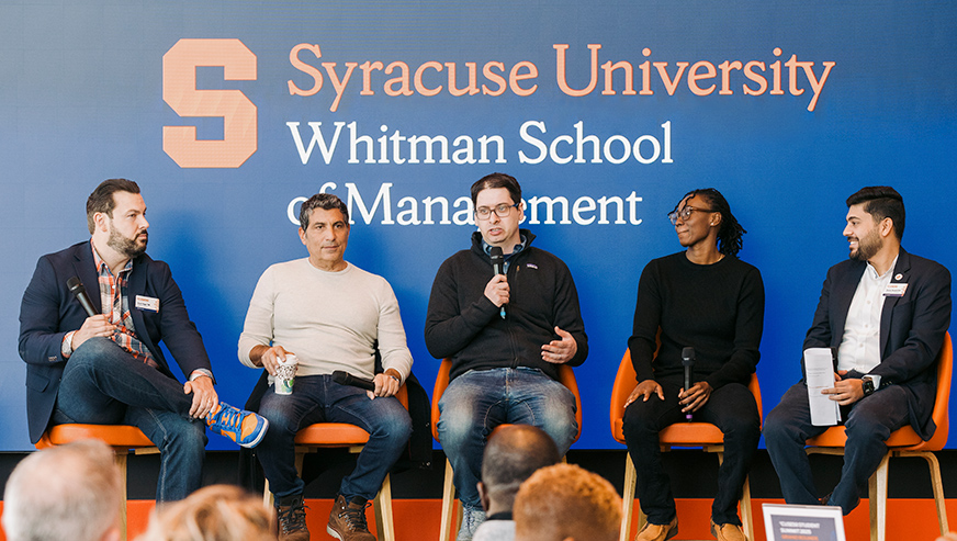 Panel on stage facilitated by Kelsey Davis, Whitman logo in background