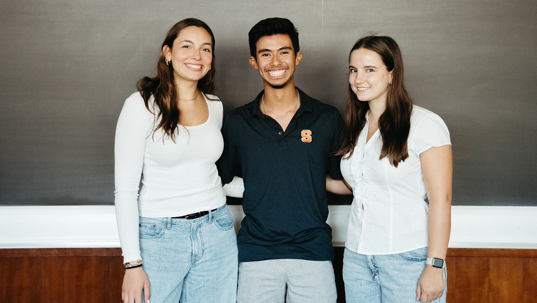 Three students posing in front of blackboard