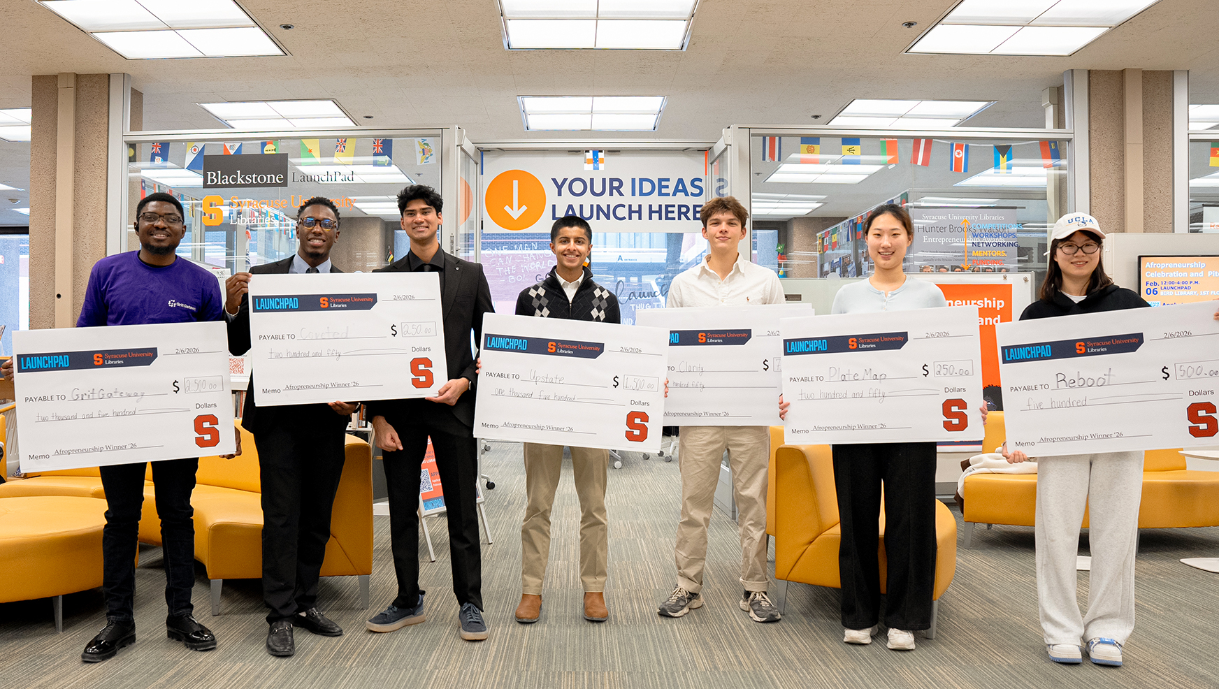 Winning students pose with their oversized checks