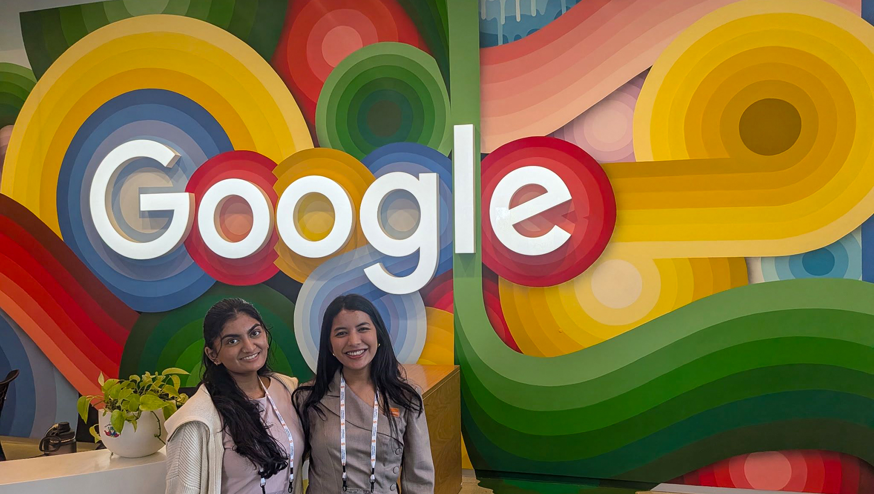 Two students posing in front of Google Sign