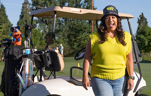 Vicki Vasil posing in front of a golf cart