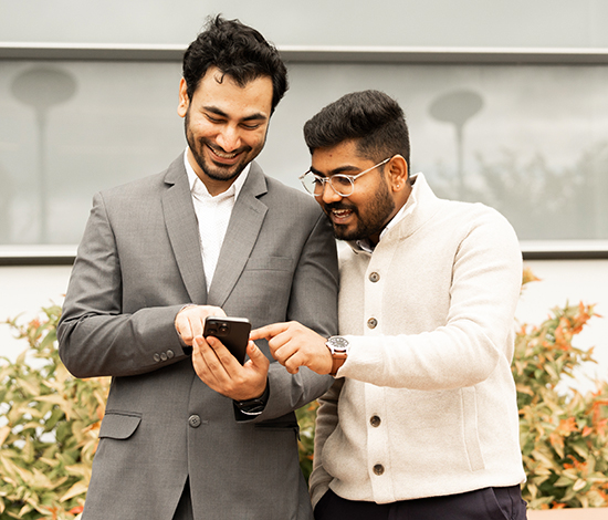 Two graduate students looking at a cellphone