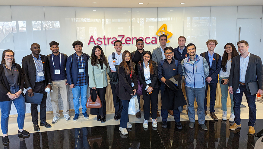 Students posing in front of Astra Zeneca logo